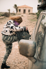 woman in camouflage clothes pouring fuel on a car fuel tank from a jerrycan