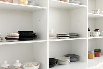 Shelf unit with set of clean dishes in kitchen