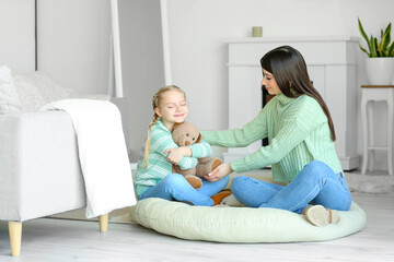 Happy little girl and her mother in warm sweaters with toy at home