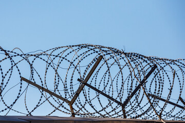 barbed wire on the wall against the blue sky