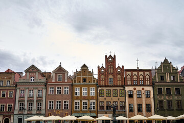 Fototapeta na wymiar facades of historic tenement houses restaurant umbrellas on the market square