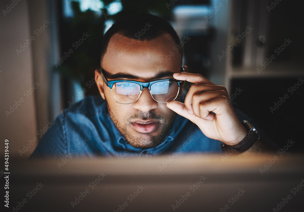 Poster right, lets do this. shot of a young businessman using a computer during a late night at work in a m