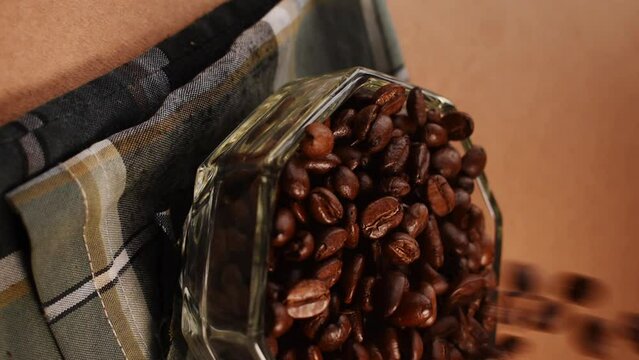Vertical video of some black coffee beans falling in a glass pot