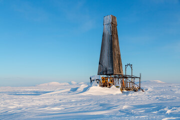 An old abandoned geological drilling rig in the snow-covered tundra. Winter Arctic landscape....