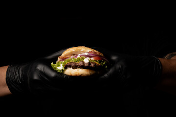 agarrando una hamburguesa a la parrilla  con la mano   - obrazy, fototapety, plakaty