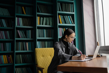 The manager is a woman with glasses working in an office coworking space, uses a laptop makes a company report on a video call