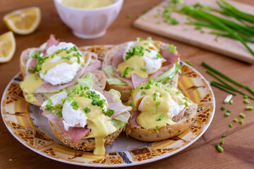 Sandwiches with poached egg, ham, lettuce, and chives, topped with sauce. Eggs Benedict