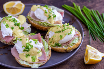 Sandwiches with poached egg, ham, lettuce, and chives, topped with sauce. Eggs Benedict