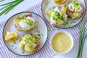 Sandwiches with poached egg, ham, lettuce, and chives, topped with sauce. Eggs Benedict