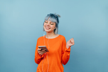 Attractive hipster girl in headphones and with a smile on her face listens to music and holds a...