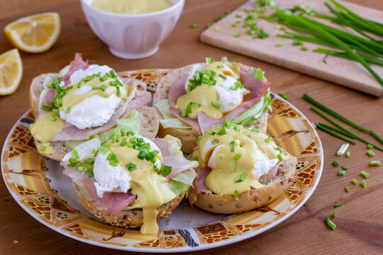 Sandwiches with poached egg, ham, lettuce, and chives, topped with sauce. Eggs Benedict