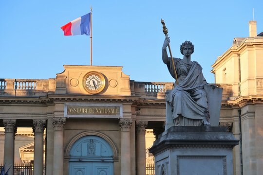 Statue allégorique de "La Loi" devant la porte d’entrée de l'Assemblée Nationale, surmontée d’un drapeau français, place du palais Bourbon à Paris - février 2022 (France)