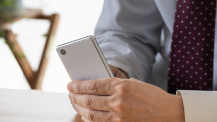 スマートフォンを操作するスーツ姿の男性。