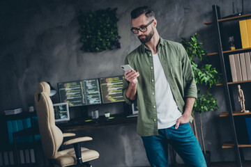 Photo of busy smart young man wear green shirt spectacles typing modern device indoors workshop...