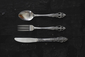 Overhead shot of silverware on black table with copy space.