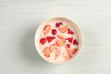 Bol de leche de avena con copos de avena y fresas sobre fondo azul pastel de madera