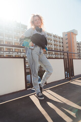 Cheerful caucasian woman in her 20s wearing 90s-inspired clothes and posing to camera with old mini cassette player. Vertical shot. . High quality photo