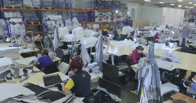 Large sewing workshop. Working process at a garment factory. Many seamstresses work in a garment factory. Seamstresses make products in a factory. Garment factory