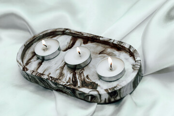 Gypsum marble decorative stand with candles on the background of silk stand.