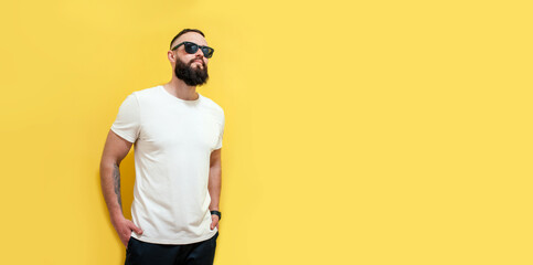 Young bearded hipster guy wearing white blank t-shirt. Studio shot on yellow background. Mock-up for print. T-shirt template.