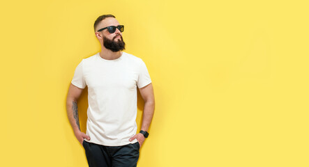 Young bearded hipster guy wearing white blank t-shirt. Studio shot on yellow background. Mock-up for print. T-shirt template.