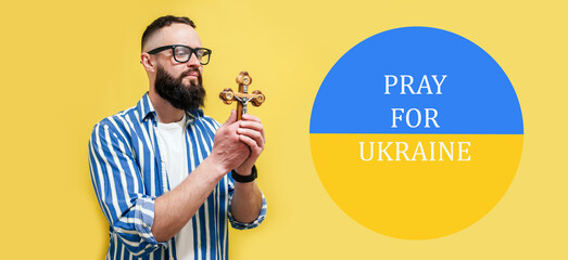 Praying religious man with a cross in his hands prays for Ukraine.