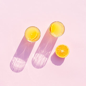 Orange Juice Drink With Orange On A Pink Background. Aesthetic Drinks Glasses With Long Shadow.