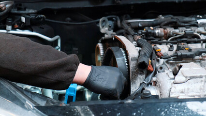 Replacing the engine timing belt in an automobile. Auto mechanic in a car repair center....