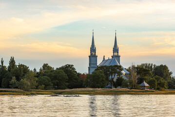 The church of Saint-Roch-des-Aulnaies at the sunset with the St. Lawrence river in the foreground (Saint-Roch-des-Aulnaies, Quebec, Canada)