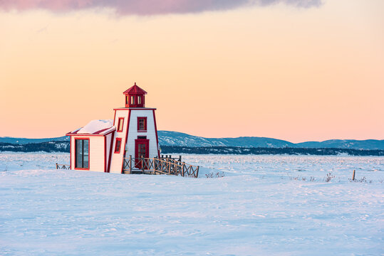Winter's view of the little lighthouse of Saint-Andre-de-Kamouraska with ice on Saint-Lawrence river and the Charlevoix in background (Quebec, Canada).