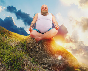 Funny man with beard in yoga position outdoor in a mountain