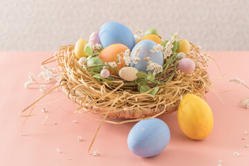 Easter eggs in nest on pink background.