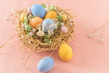 Fototapeta na wymiar Easter eggs in nest on pink background.