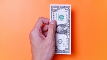 Man's hand is making a payment. Business Investment Economy Saving Loan Income Money and Finance concept. Male hand showing dollar cash on an orange background. One Dollar 1 USD. Prosperity concept.