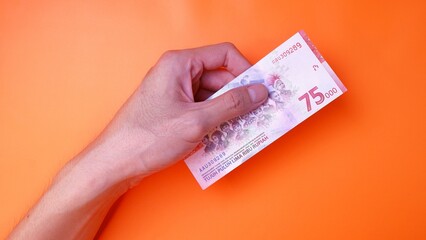Indonesian Rupiah the official currency of Indonesia. Man's hand is making a payment. Male hand...