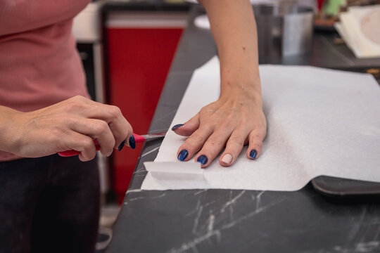 Closeup Of Person's Hands Cutting An Oil Paper For Baking