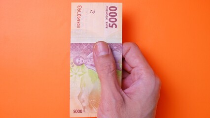 Indonesian Rupiah the official currency of Indonesia. Man's hand is making a payment. Male hand...