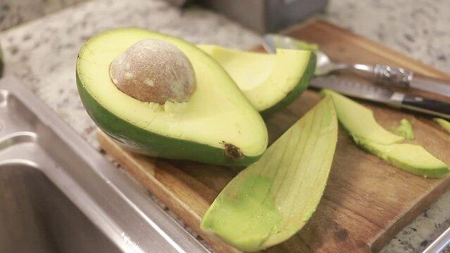 Mitades de aguacate fresco con semilla en el meson de la cocina.