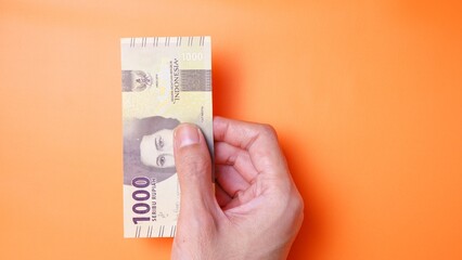 Indonesian Rupiah the official currency of Indonesia. Man's hand is making a payment. Male hand...