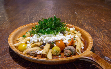 Pasta pan with mushrooms, tomatoes and feta cheese for menu in restaurant, cafe or hotel copy space