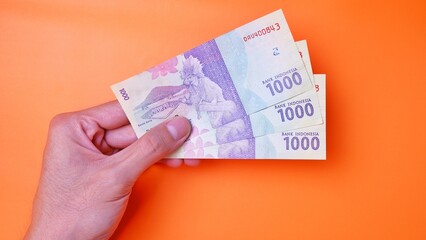 Indonesian Rupiah the official currency of Indonesia. Man's hand is making a payment. Male hand...