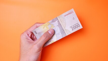 Indonesian Rupiah the official currency of Indonesia. Man's hand is making a payment. Male hand...