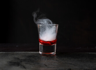 bebida con reacción química por hielo seco, con líquido rojo sobre piedra y fondo negro