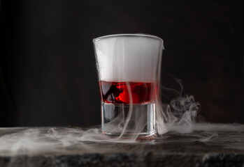 bebida con reacción química por hielo seco, con líquido rojo sobre piedra y fondo negro