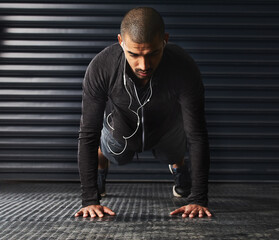 It doesnt get easier, you just get stronger. Shot of an athletic young man doing pushups in the gym.