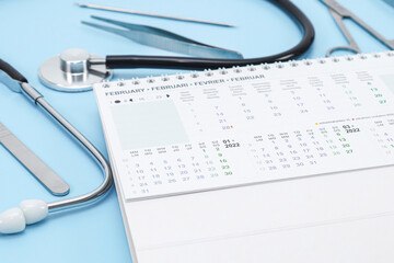 February 2022 calendar, stethoscope and surgical instrument with selective focus on a light blue .