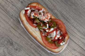 Overhead view of spicy variety of hotdog with sliced jalapenos, tomatoes, and cream cheese for a flavor explosion
