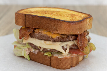 Enormous garlic bread double deck cheeseburger loaded wih bacon and lettuce for a huge appetite