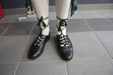 Closeup of a man's legs wearing white socks and traditional Scottish shoes