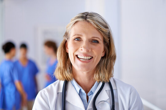 Medicine Is Her Passion. Portrait Of A Mature Female Doctor With A Group Of Nurses Standing In The Background.